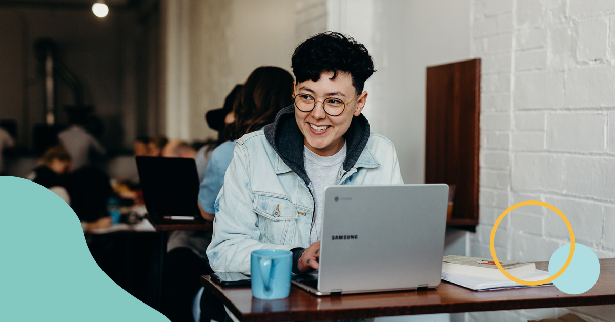 Non-binary person working on a laptop in cafe